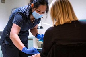 Occupational health nurse Jeanne Brueggemann treats an employee during a visit to the University Employee Occupational Health Clinic.