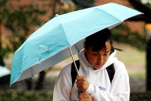 UNC-Chapel Hill student sheltering using an umbrella.